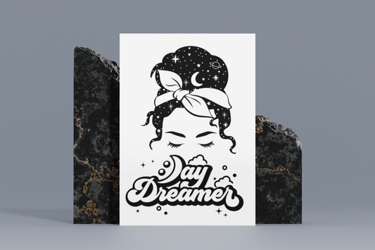 An 8x10 black and white metal sign featuring an intricate celestial design around the serene face with “Day Dreamer” text below.